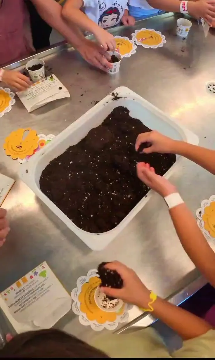 Mani di bambini che riempiono di terra dei vasetti durante un laboratorio