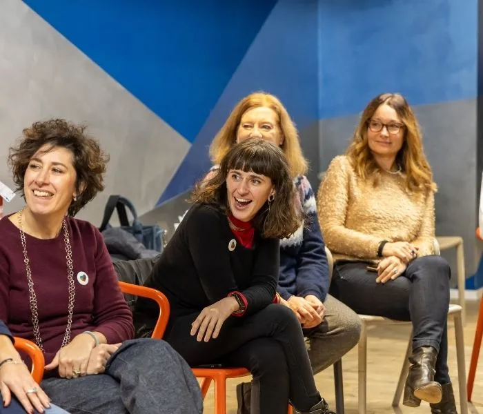 Tre collaboratrici del team Kid Pass sorridono sedute in cerchio